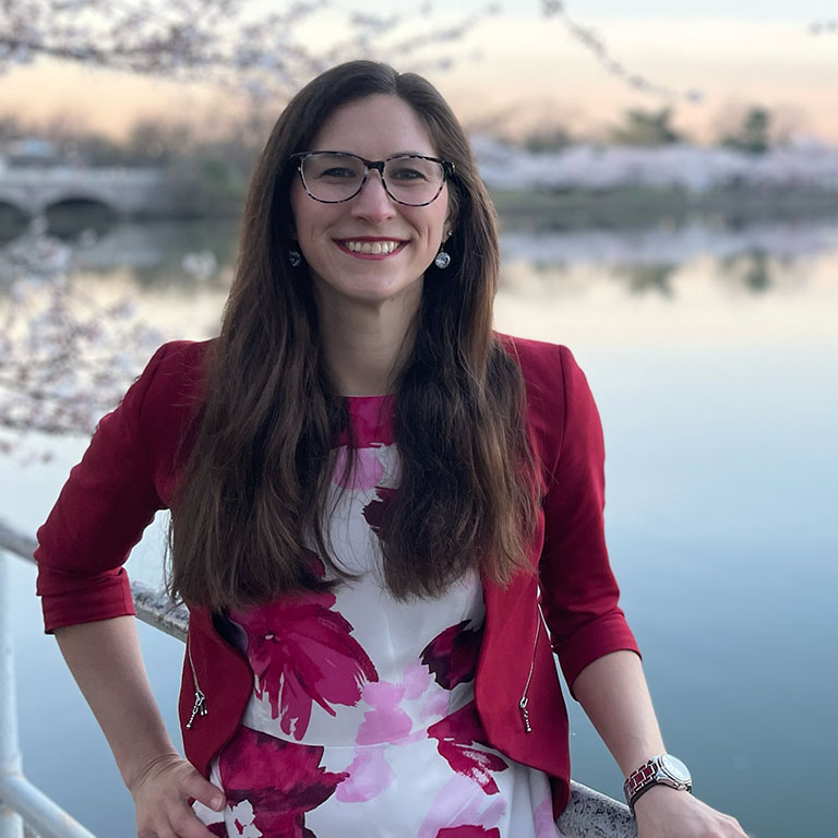 A headshot of Margaret Jacobson, who poses among the cherry blossoms in the Rotunda in Washington, DC.