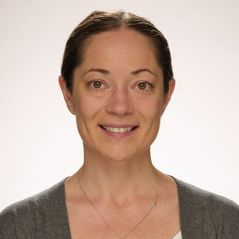 A headshot of Sophia Vinci-Booher, who wears a beige sweater and poses against a white background.